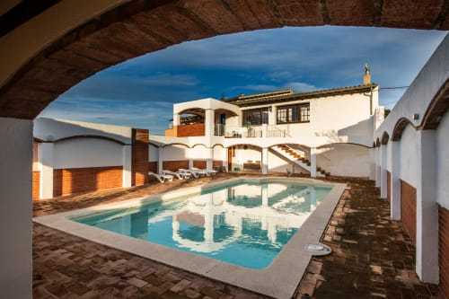 Masia Rural Ca l'Eloi Janet, piscina y patio en Barcelona con agua turquesa y edificios blancos