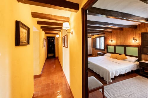 Pasillo amarillo brillante que conduce a dormitorio con vigas de madera en Masia Rural Ca l'Eloi Janet cerca de Barcelona