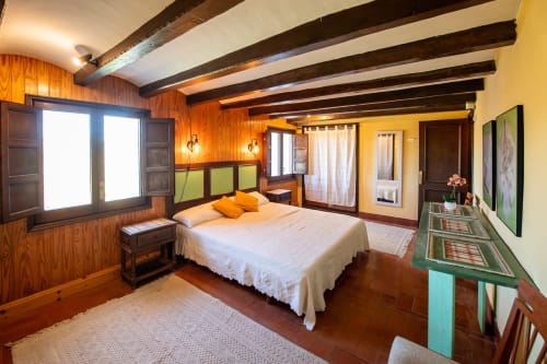 Dormitorio amplio en Masía Rural Ca l'Eloi Janet con vigas de madera, toques naranjas y encanto rústico barcelonés