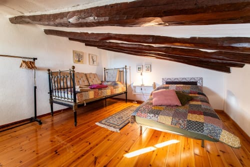 Dormitorio rústico con vigas de madera, dos camas y piso de barro en Masía Rural Ca l'Eloi Janet cerca de Barcelona