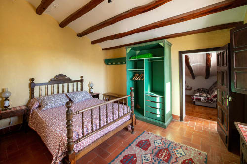 Dormitorio rústico en Masia Rural Ca l'Eloi Janet cerca de Barcelona con vigas de madera, cama de latón y armario verde
