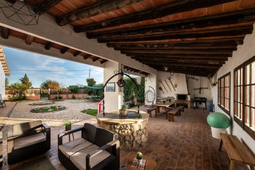 Patio cubierto en Masía Rural Ca l'Eloi Janet cerca de Barcelona con vigas rústicas, zona de descanso y vistas al campo