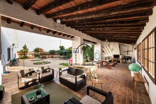 Spacious covered patio at Masia Rural Ca l'Eloi Janet near Barcelona with lounge seating, dining tables, and rustic wooden