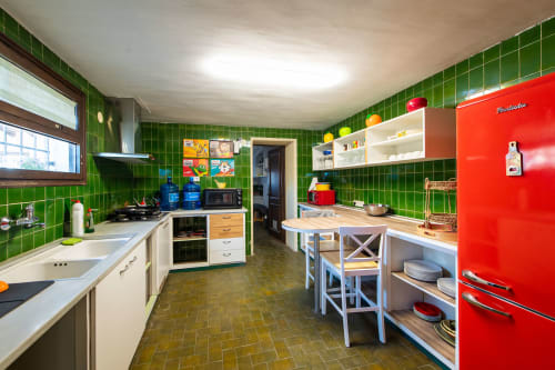 Cocina retro vibrante con paredes de azulejos verde brillante, refrigerador rojo y mesa de comedor de madera en Masia Rural Ca l'Eloi Janet