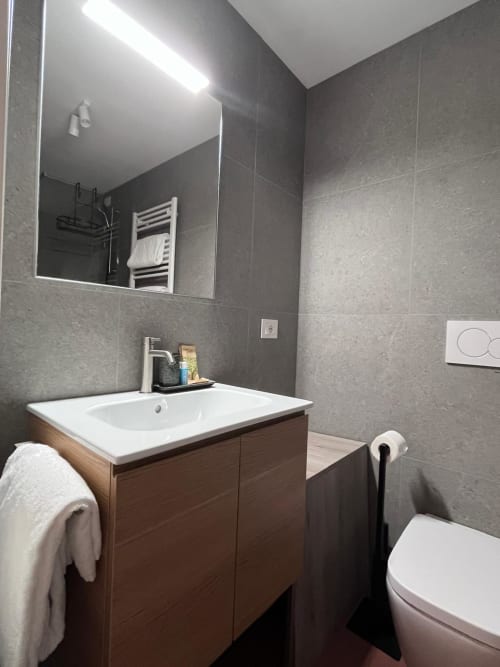 Bagno moderno del Casanova Hideaway Venezia con rivestimento in piastrelle grigie, mobile lavabo in legno e scaldasalviette