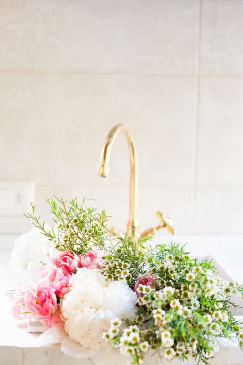 Elegant floral arrangement with pink peonies and white daisies in a brass sink at Alessia's Place Como suite
