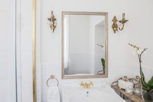 Elegant bathroom sink in Alessia's Place Como apartment with gold fixtures, marble frame mirror, crystal sconces, and white