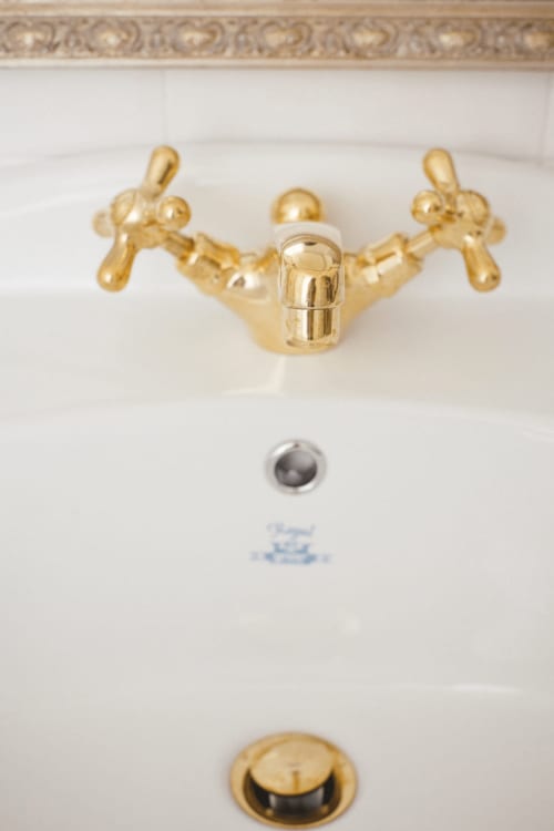 Gold cross-handle faucet on white sink basin at Alessia's Place, Como apartment suite