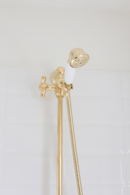 Elegant brass shower head with white porcelain accents and flexible hose at Alessia's Place luxury suite in Como