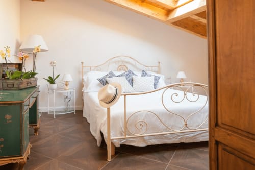 Elegant bedroom suite at Alessia's Place Como with ornate metal bed, white bedding, and city view