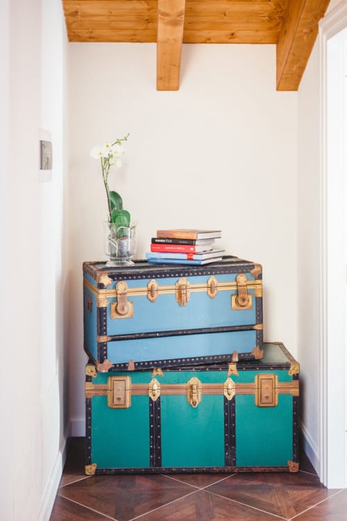 Vintage blue and teal suitcases stacked with books and orchid plant in Alessia's Place Como apartment suite