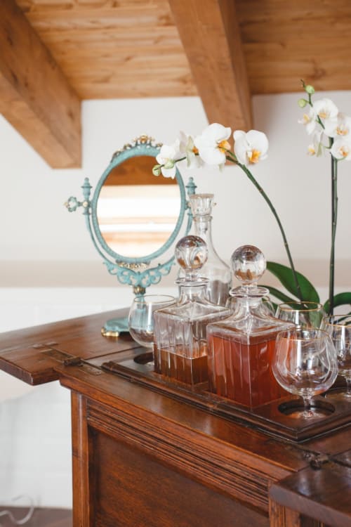 Elegant vanity setup at Alessia's Place Como with ornate turquoise mirror, crystal perfume bottles, and white orchids