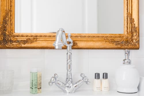 Elegant bathroom sink at Alessia's Place Como with chrome fixtures, ornate gold-framed mirror, and complimentary toiletries