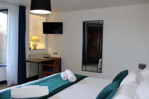 Modern hotel bedroom at Domaine des Piéris with double bed, desk, TV, and garden view in Grandcamp-Maisy