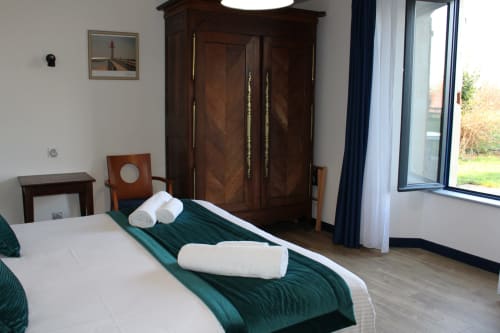 Spacious double bedroom at Domaine des Piéris with garden view, dark wood wardrobe, and modern amenities in Grandcamp-Maisy