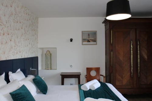 Elegant double bedroom at Domaine des Piéris with twin beds, dark headboards, teal accents, and wooden wardrobe in
