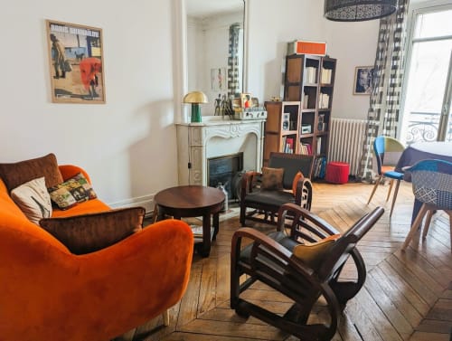 Salon éclectique de l'appartement parisien avec fauteuils en velours orange, cheminée et décoration vintage à la Conciergerie Saint Martin