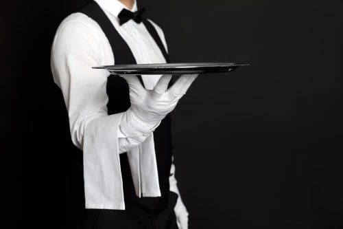 Serveur en tenue de gala tenant un plateau de service à l'hôtel Conciergerie Saint Martin Paris