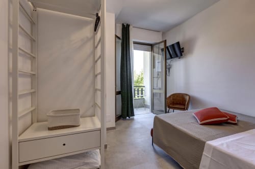 Bright hotel bedroom at Palazzo Belvedere with bed, bathroom, balcony overlooking Chianciano Terme, TV, and modern