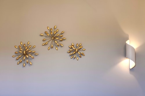 Modern wall décor with three golden starburst ornaments and a contemporary white wall sconce light fixture in a Palazzo