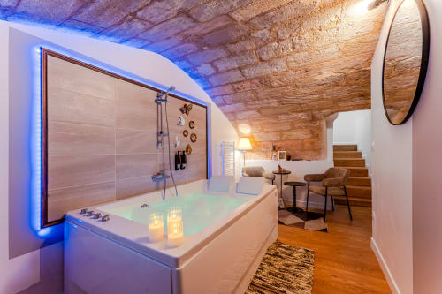 Luxury spa bathroom in Bordeaux apartment with illuminated jacuzzi, rainfall shower, and exposed brick ceiling
