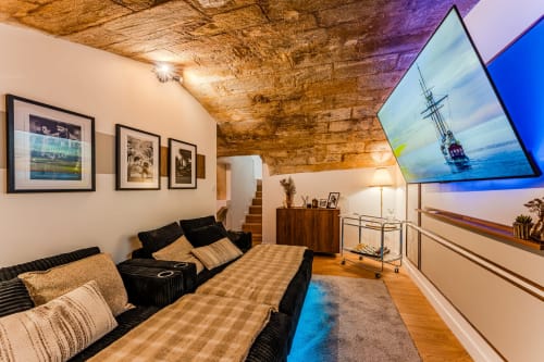 Wellkhome Bordeaux Suite d'Exception: vaulted ceiling lounge with black sofa, wooden furniture, framed art, flat-screen TV