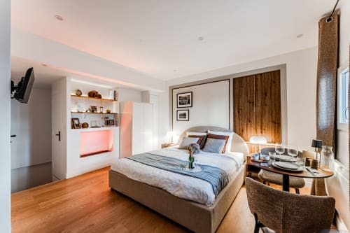 Luxurious suite at Wellkhome Bordeaux with king bed, spa tub, flat-screen TV, wooden furniture and city view