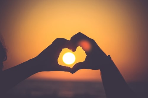 Couple making heart shape with hands at sunset, Les Granges Indigo B&B, Fossemagne France