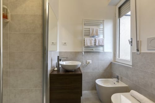 Modern bathroom at Palazzo Belvedere hotel with dual sinks, shower enclosure, bidet, and heated towel rack in Chianciano