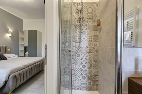 Modern bathroom with patterned tile shower at Palazzo Belvedere hotel in Chianciano Terme, connecting to bedroom with bed and