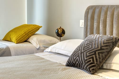 Elegant bedroom at Palazzo Belvedere with white bedding, yellow and patterned pillows, and upholstered headboard in