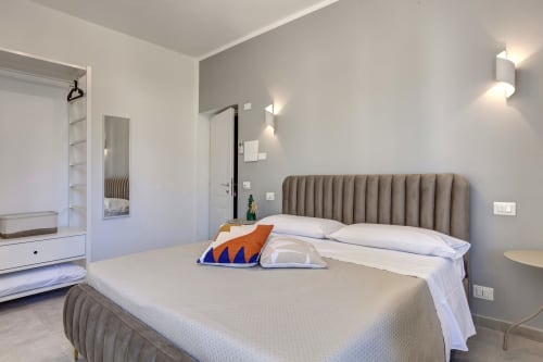 Modern bedroom at Palazzo Belvedere with beige bed, gray upholstered headboard, and contemporary furnishings in Chianciano