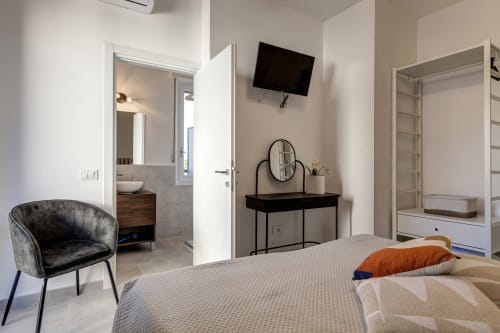 Modern bedroom at Palazzo Belvedere with bed, flat-screen TV, vanity desk, and ensuite bathroom in Chianciano Terme