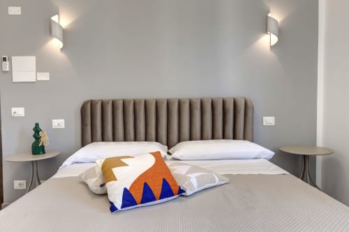 Modern bedroom at Palazzo Belvedere hotel with taupe channel headboard, white bedding, and colorful geometric pillow