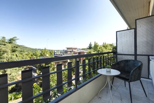 Balcony with black railing at Palazzo Belvedere hotel in Chianciano Terme, featuring chair, table, and scenic valley views