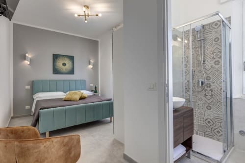 Modern bedroom at Palazzo Belvedere with turquoise bed, ensuite bathroom, and contemporary decor in Chianciano Terme