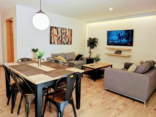 Moderna área de estar de planta abierta en el hotel Casa Donceles en Ciudad de México con comedor, sofás grises, televisión e iluminación colgante