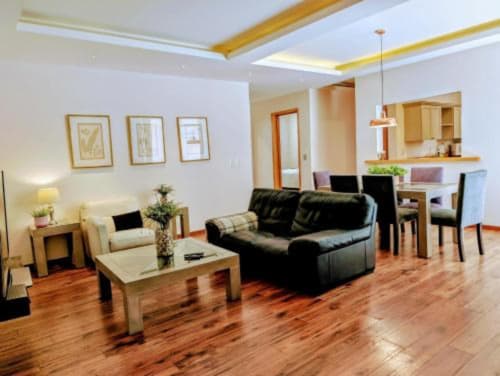 Suite del hotel Casa Donceles en Ciudad de México con sofá de cuero negro, piso de madera y cocina abierta