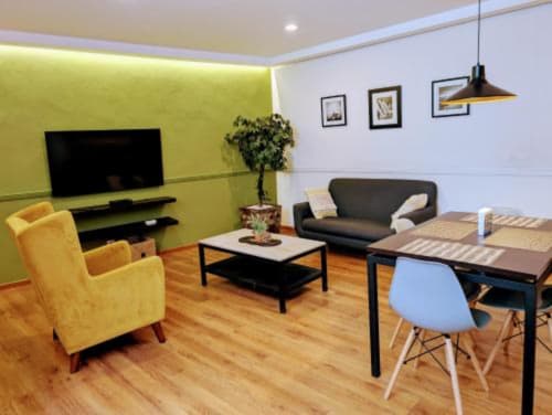 Espacio moderno de vida en el hotel Casa Donceles en Ciudad de México con pared amarilla, televisor, sofá negro y área de trabajo