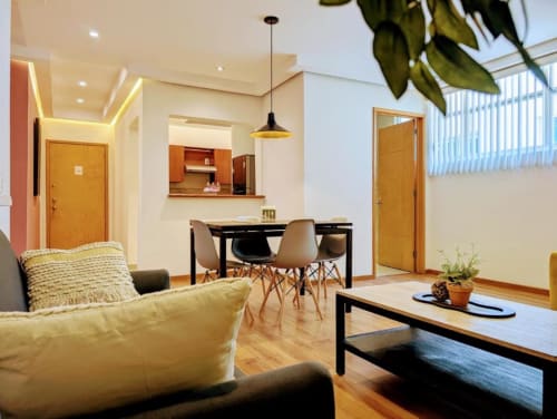 Departamento moderno de planta abierta en Casa Donceles, Ciudad de México, con sofá amarillo, comedor y zona de cocina