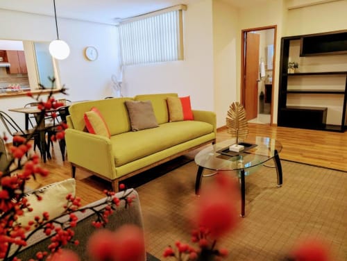 Sofá amarillo brillante con cojines coloridos en la sala del hotel Casa Donceles, Ciudad de México