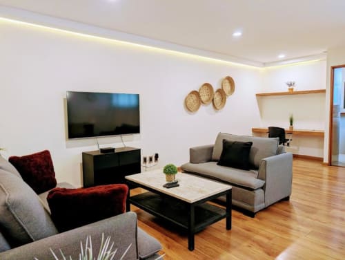 Sala de estar moderna del hotel Casa Donceles en México con sofá gris, sillas rojas y televisor de pantalla plana