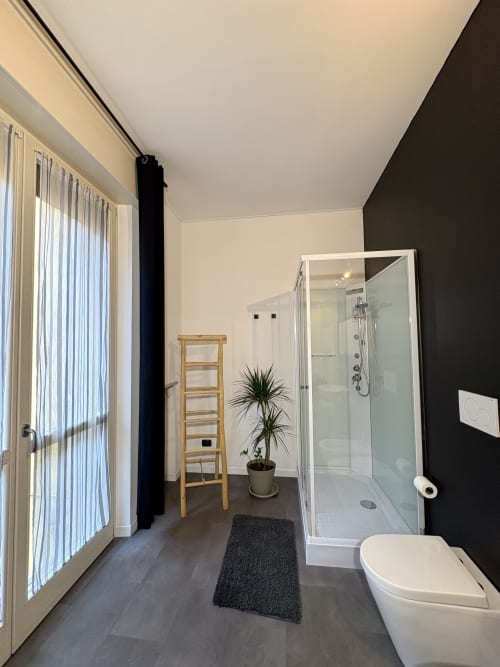 Moderno bagno dell'hotel Le Arche a Verona con doccia, wc, scala in legno e pianta in vaso