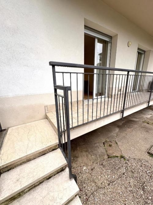 Moderna ringhiera in metallo nero sul balcone dell'appartamento con gradini, pareti color crema e porte in vetro a Le Arche Verona