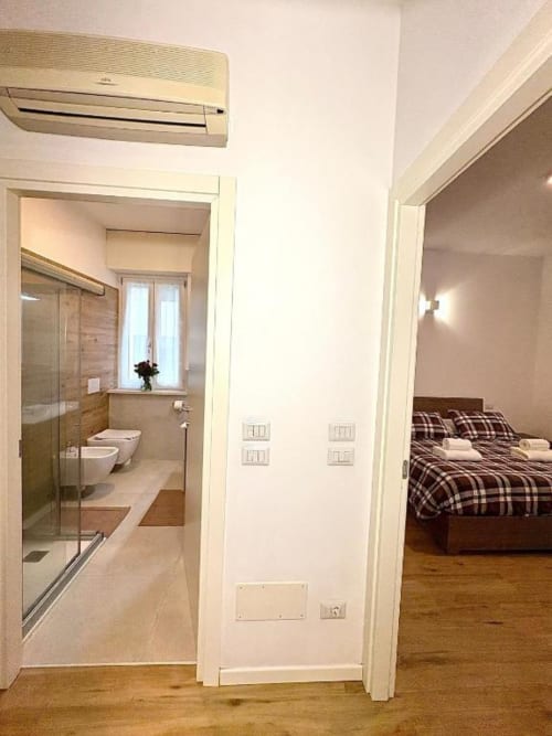 Appartamento Dimora Vittoria a Verona: camera da letto con biancheria a quadri, bagno con doccia e condizionamento d'aria