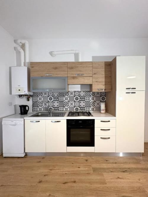 Cucina moderna con mobili color panna, dettagli in legno e rivestimento a piastrelle decorate nell'appartamento Le Arche a Verona