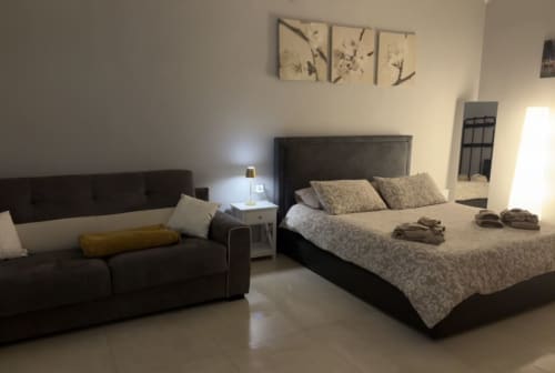 Camera moderna al San Carlo 104 BnB a Caserta con letto nero, divano, biancheria fantasia e vista sulla città