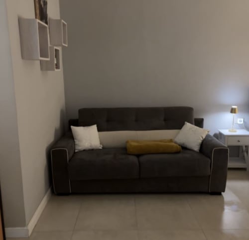 Divano moderno scuro con cuscini bianchi nella Camera 101 di San Carlo 104 BnB, Caserta, Italia