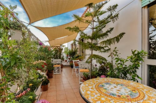 Terrazza del Roof Garden B&B di Alghero con piante in vaso, vele ombreggianti e tavolo decorativo in Sardegna