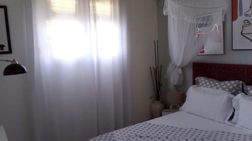 Chambre lumineuse au gîte Le Nid De Bellemont avec literie à pois, tête de lit rouge, rideaux voilage, vue mer et design moderne